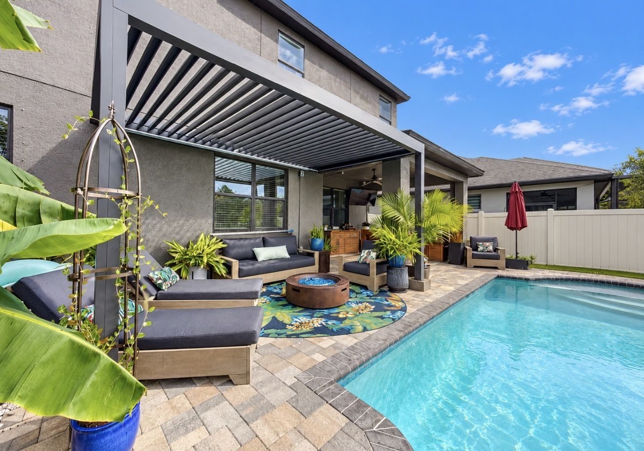 Pergola, pool deck and lounge seating behind the home