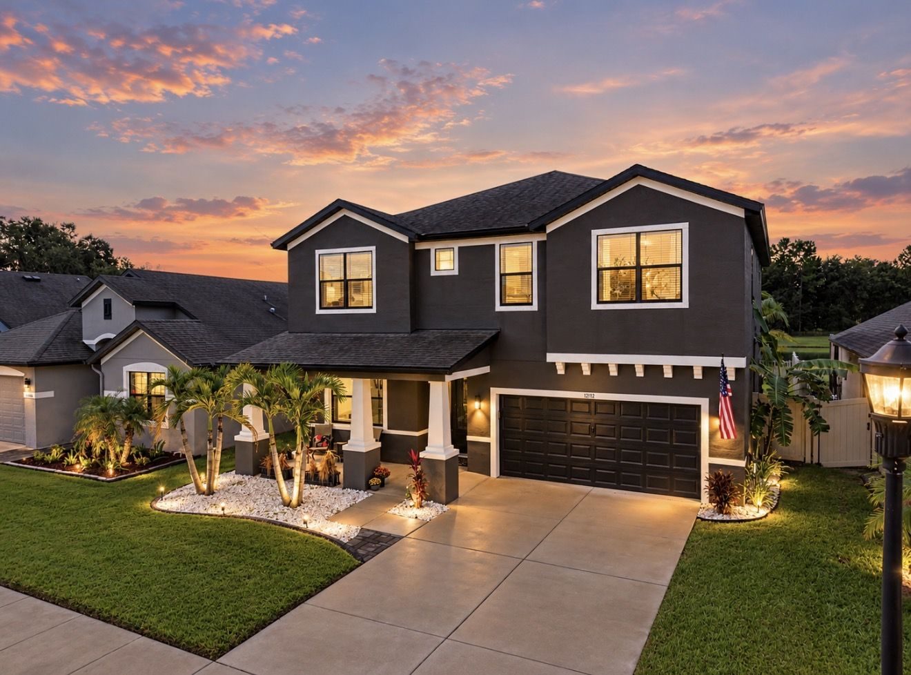 Front of 12112 Creek Preserve Dr at twilight, charcoal two-story home with lit palms and porch